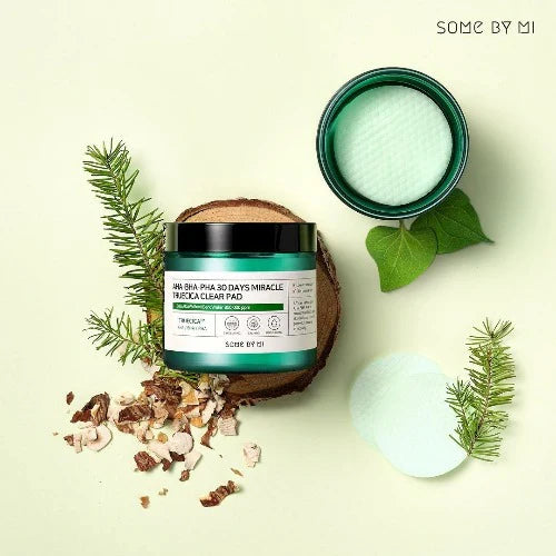 Cosmetic product with green packaging and natural elements on a light background, featuring 'SOME BY MI' branding.