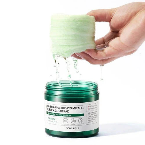 Hand opening a green skincare product container with a white label.