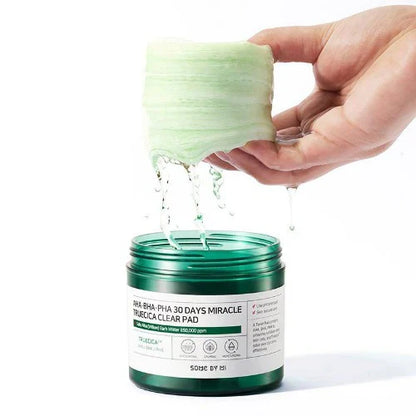 Hand opening a green skincare product container with a white label.
