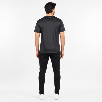A man viewed from behind wearing a black short-sleeve t-shirt, black pants, and white sneakers against a plain white studio background.