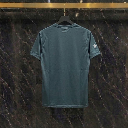 A dark teal short-sleeve t-shirt hanging on a black hanger against a dark marble wall with gold veining.