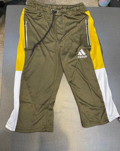 A pair of Adidas athletic jogger pants in olive green, featuring bright yellow and white color-blocked side panels, silver zipper details, and the white Adidas logo on the left thigh.